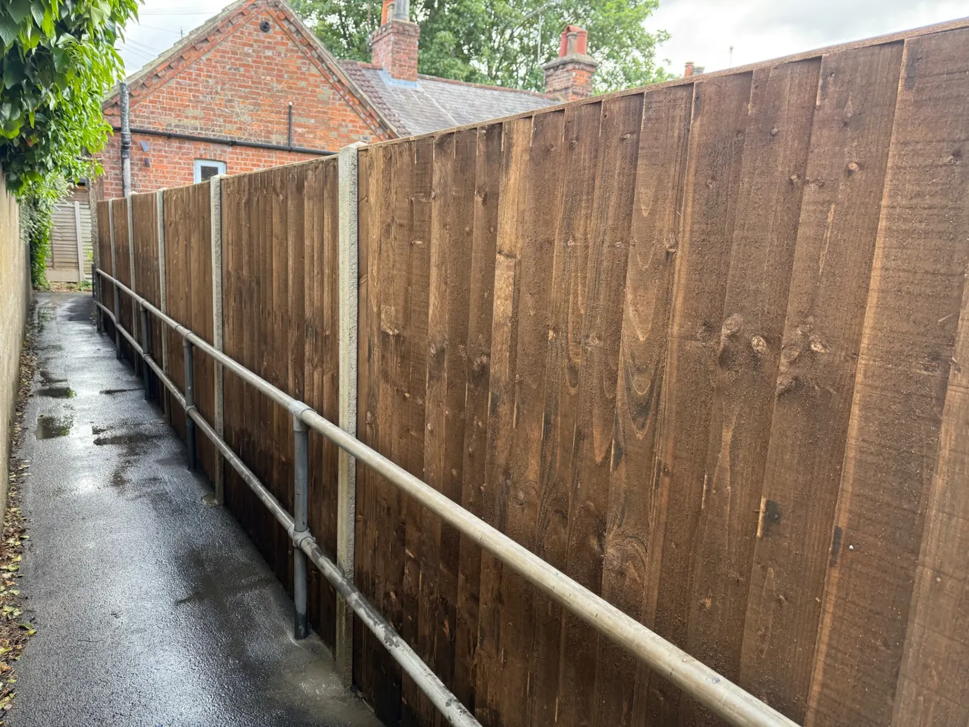 Tall closeboard boundary fence beside an access lane