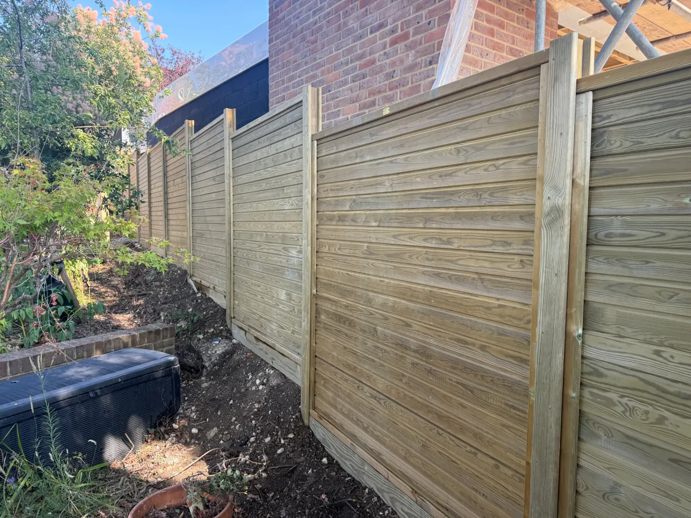 Horizontal slatted fence line running beside a brick house
