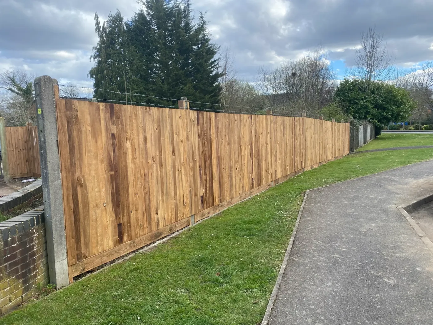 Tall closeboard fence line running along a roadside boundary