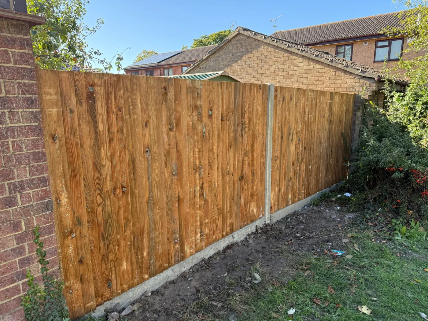 Closeboard boundary fence built alongside a brick wall