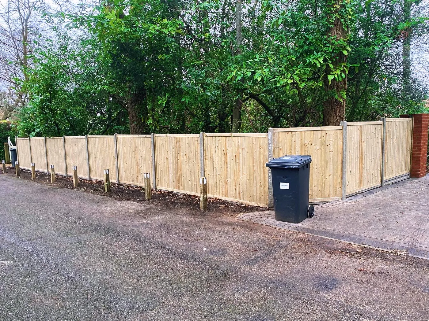 New timber boundary fence panels along a driveway entrance
