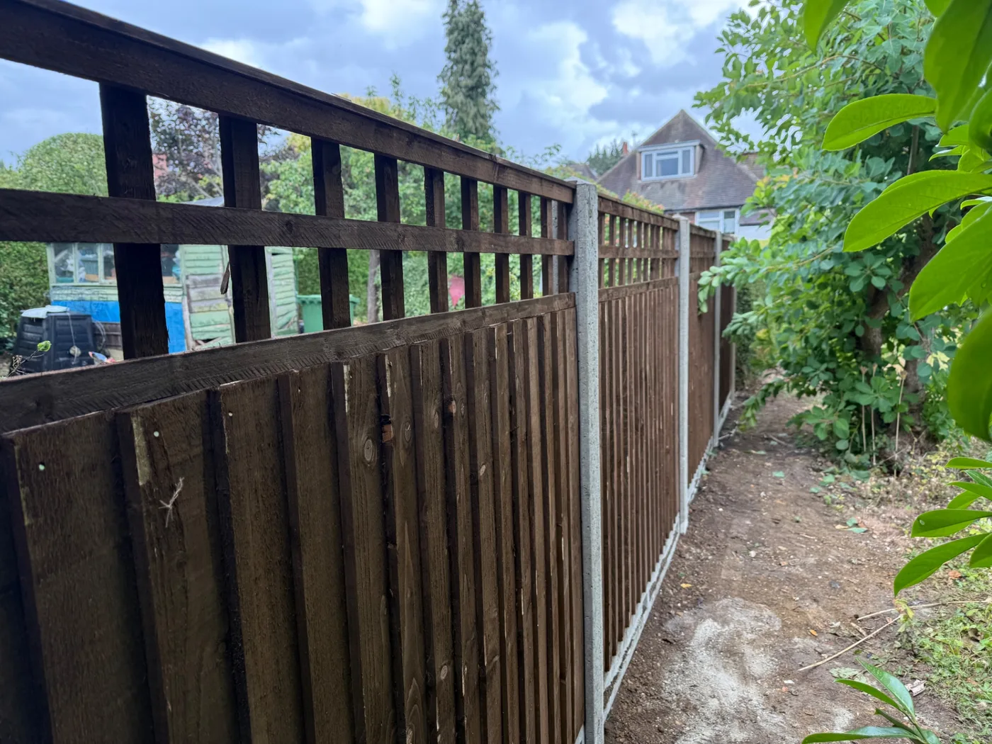 Dark stained feather edge fence panels with square trellis tops
