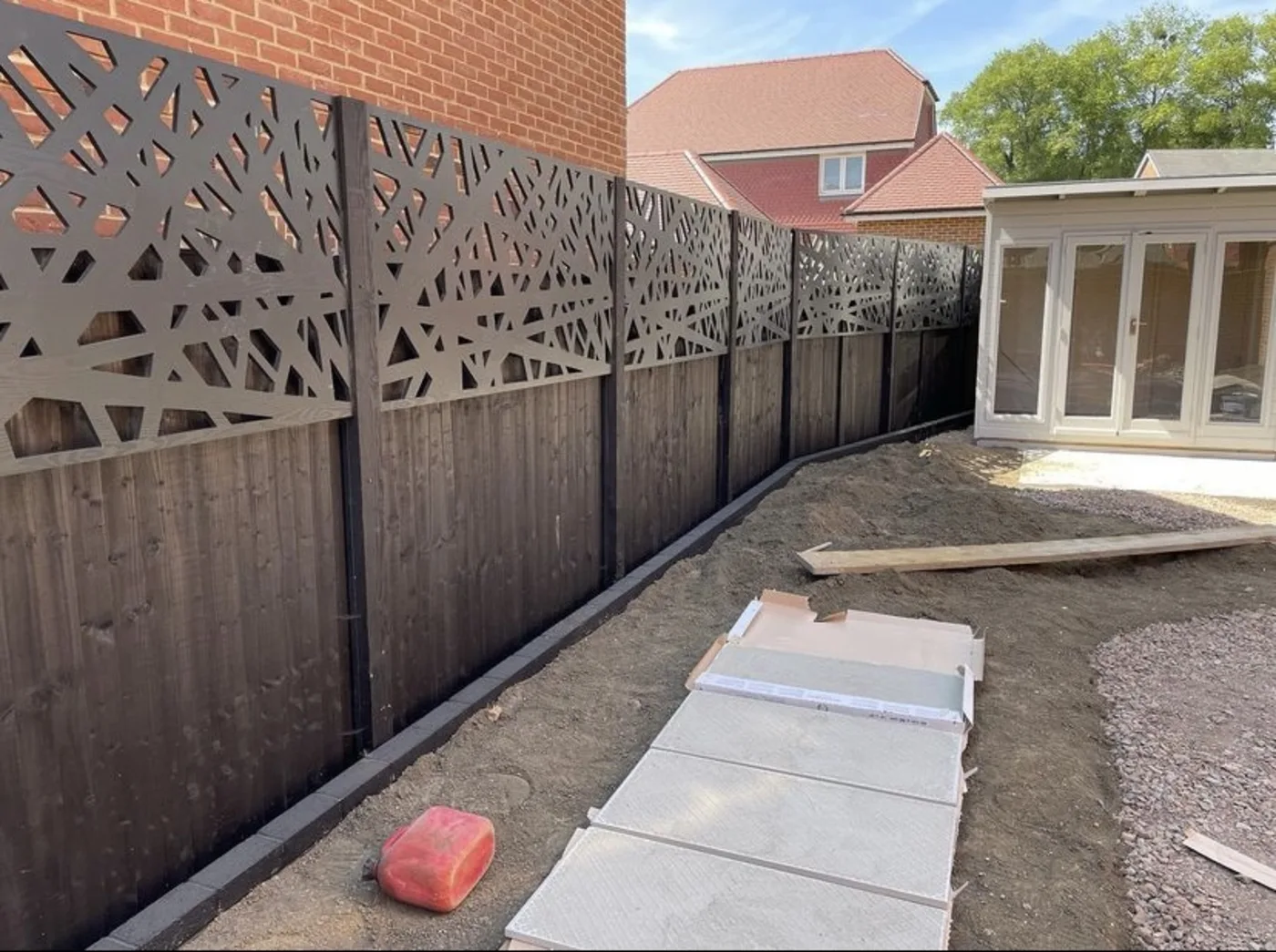 Decorative laser cut fence toppers above dark garden fence panels