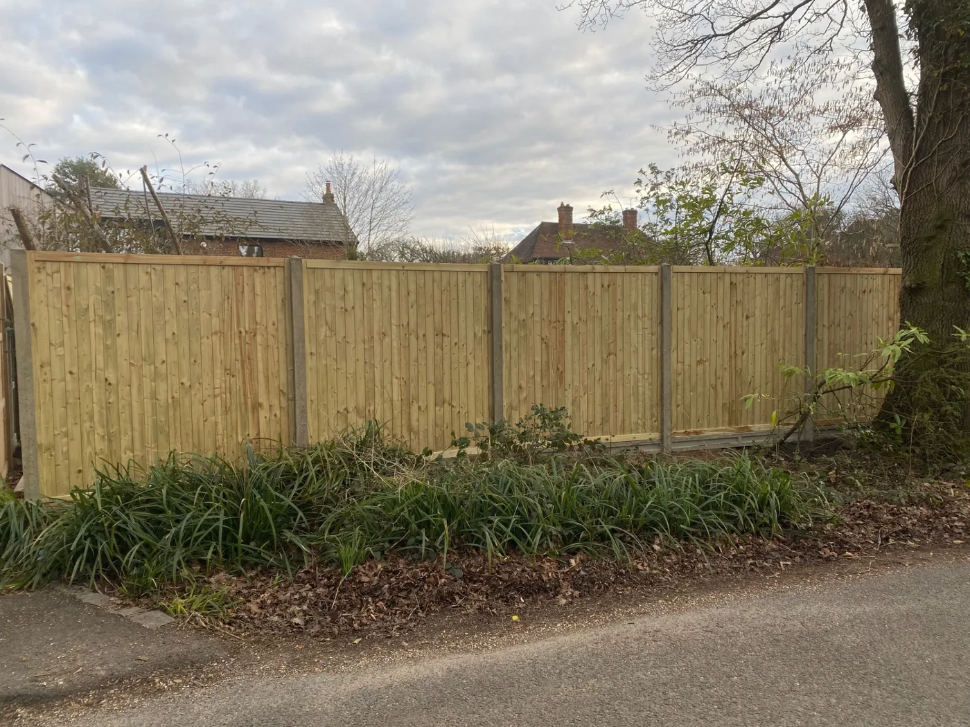 Long run of new fence panels along a roadside boundary