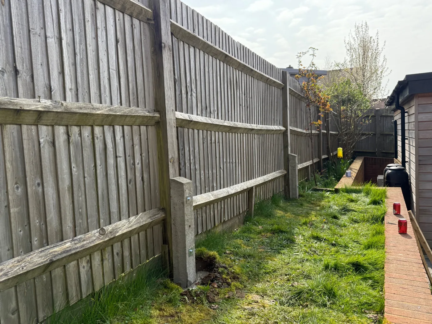 Leaning weathered fence panels with concrete posts awaiting repair